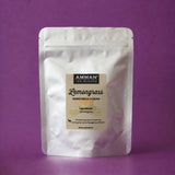 Envase Doypack plateado de Lemongrass Amman Tea Blends con propiedades para desintoxicar y calmar, sobre fondo morado.