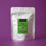 Envase Doypack plateado de Poleo Amman Tea Blends con etiqueta verde, propiedades expectorantes y para eliminar gases, sobre fondo morado.