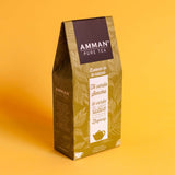Caja de té verde Sencha Amman Pure Tea en envase dorado sobre fondo amarillo, infusión suave y refrescante de hojas de té verde.